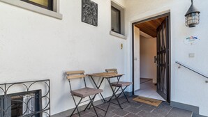 Un escalier menant à une entrée dotée d’une porte, deux tables pliantes, un portail en métal et un luminaire fixé au mur.