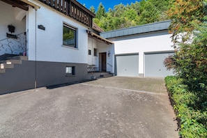 En tvåvåningsbyggnad med en balkong, ett garage och en asfalterad uppfart.