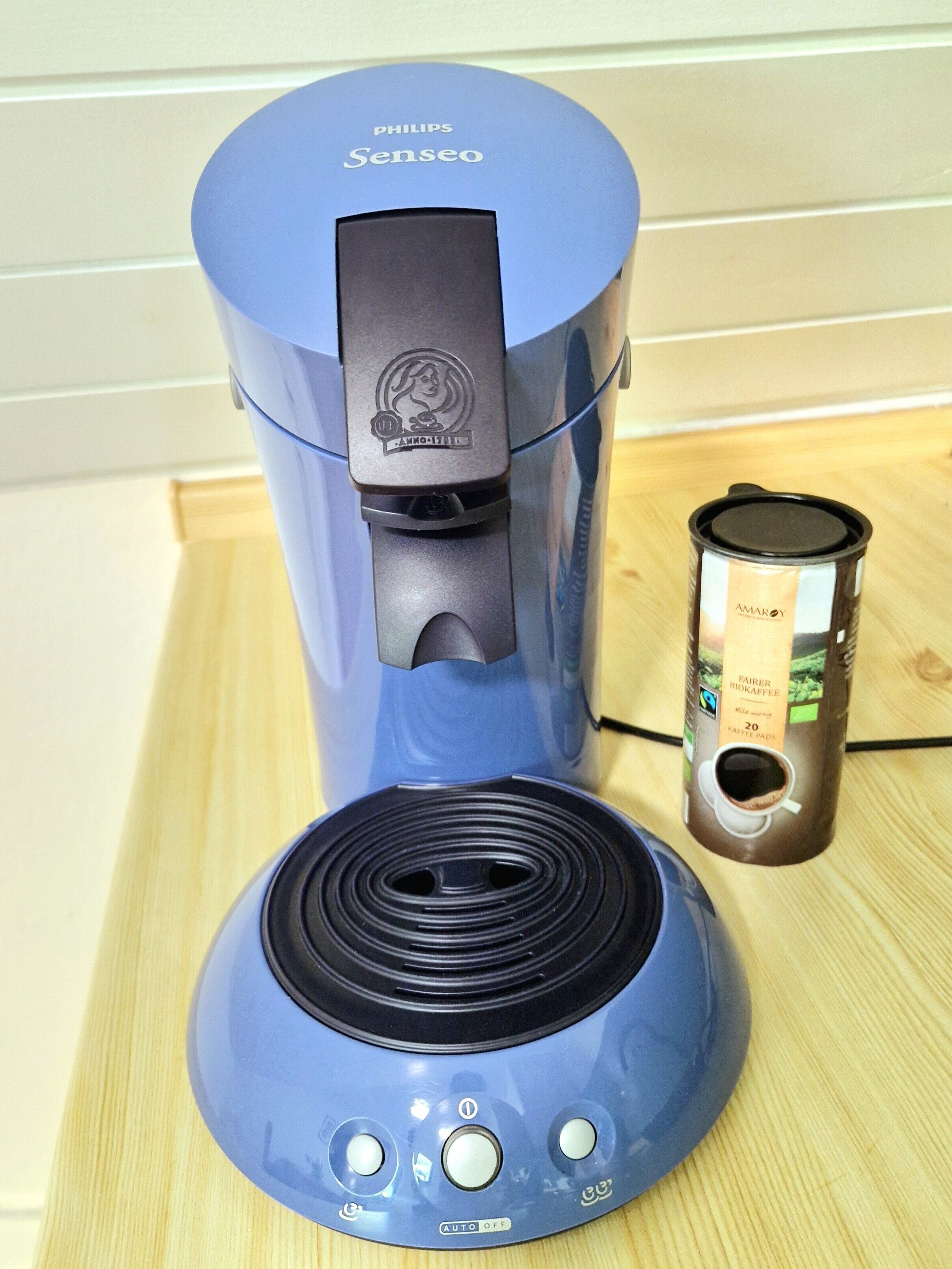 A blue Philips Senseo coffee maker with a coffee pod holder beside it.