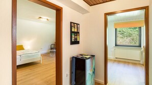 Une pièce comprenant un lit, une petite table, une fenêtre donnant sur un espace verdoyant et un tableau d’affichage fixé au mur.