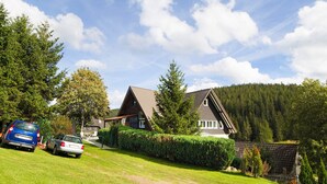 Ein Haus mit geneigtem Dach, einem sichtbaren Schornstein und einem gepflegten Rasen.