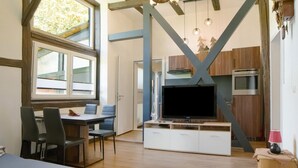 Eine moderne Küche mit einem großen Fernseher, Holzschränken und einem Essbereich mit Stühlen.