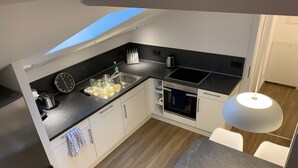 A modern kitchen with a built-in oven, a coffee maker, and a sink. - Apartment 'Felix Living 7' with Private Terrace and Wi-Fi (Passau)
