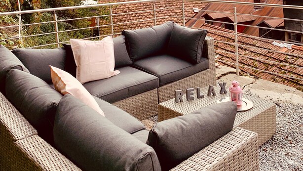 A wicker sofa with cushions, a small table with a lantern, and the word 'RELAX' on it. - Apartment 'Felix Living 7' with Private Terrace and Wi-Fi (Passau)
