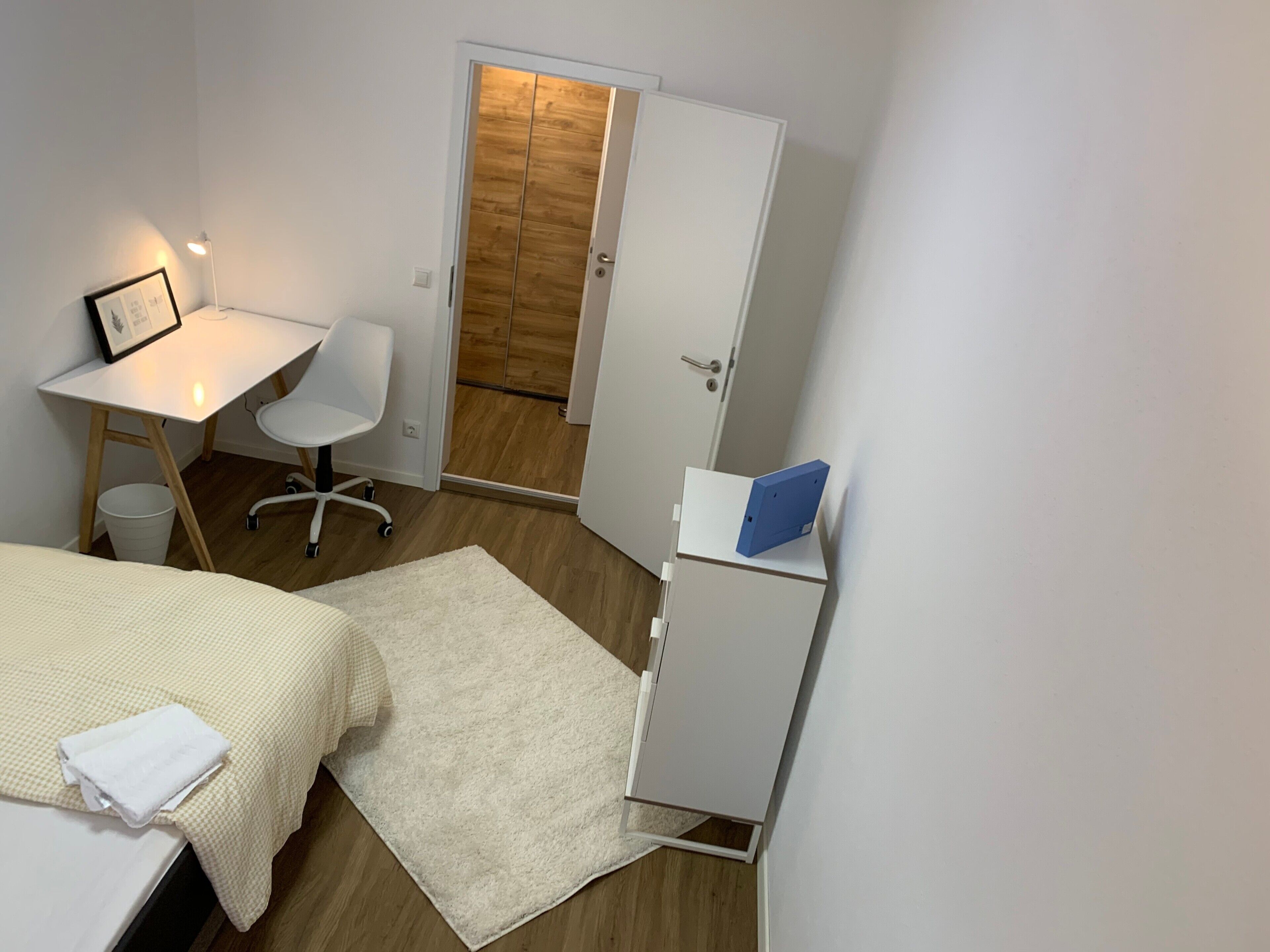 Une chambre à coucher comprenant un lit, un bureau, une chaise, une armoire et une porte.