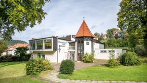 Ein Gebäude mit Glasfassade, rotem Ziegeldach und einem kleinen turmartigen Aufbau.