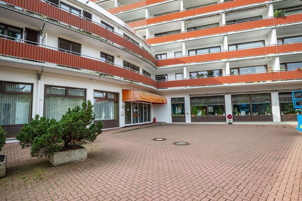 Un edificio de varios pisos con un patio, balcones y plantas en macetas.