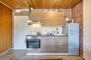 Eine moderne Küche mit Holzausstattung, einem Edelstahlbackofen, einer Spüle und einem Kühlschrank.