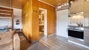 Eine moderne Küche mit Holzschränken, einem Edelstahlbackofen und einer Wand mit Backsteinverkleidung.