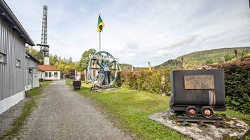 A gravel path leading to a building with a large water wheel and a flagpole.
