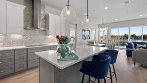 Una cocina moderna con una isla grande, taburetes de bar e iluminación colgante.
