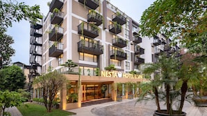A multi-story hotel with balconies, a well-maintained garden, and a clear sign reading "NESTA HOTEL SPA". - Nesta Hotel & Spa (Hanoi)