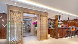 A modern bar area with a marble countertop, bar stools, and a decorative wall with a geometric pattern. - Nesta Hotel & Spa (Hanoi)