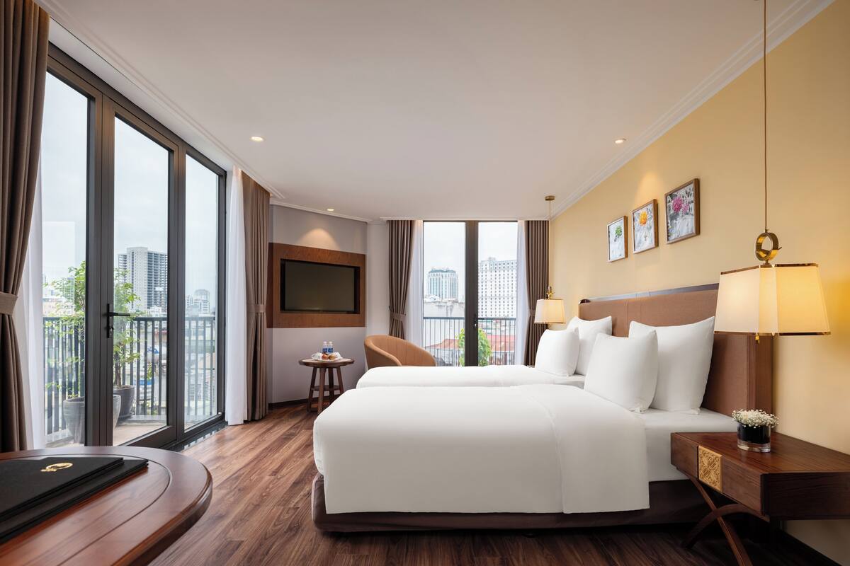 Hotelkamer met een groot bed, een bureau, een stoel, een televisie en uitzicht op de stad.