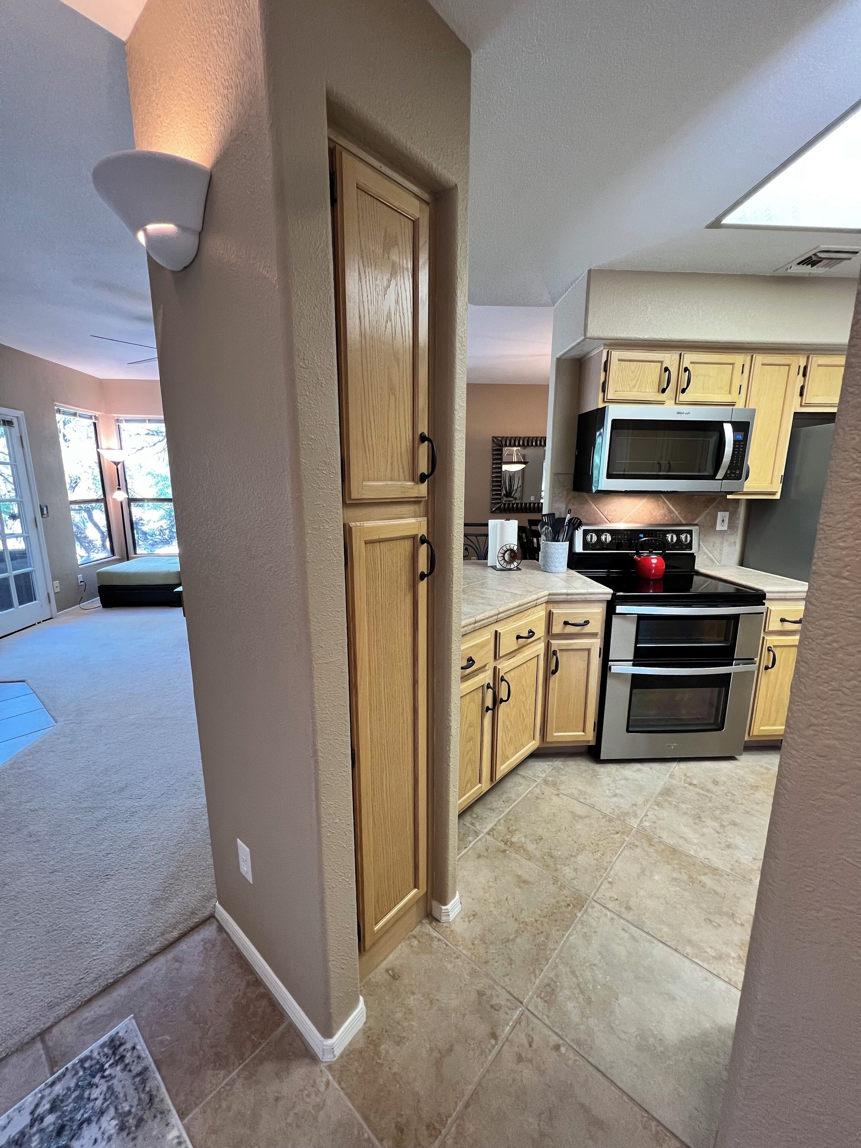 A modern kitchen with wooden cabinets, a stainless steel oven, and a microwave.