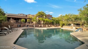 A swimming pool with lounge chairs and a covered area, surrounded by trees and buildings. - Canyon Vista 🌵3br Retreat: Views, Hiking, Birds, Heated Pools, Spas, Court, Gym (Tucson)