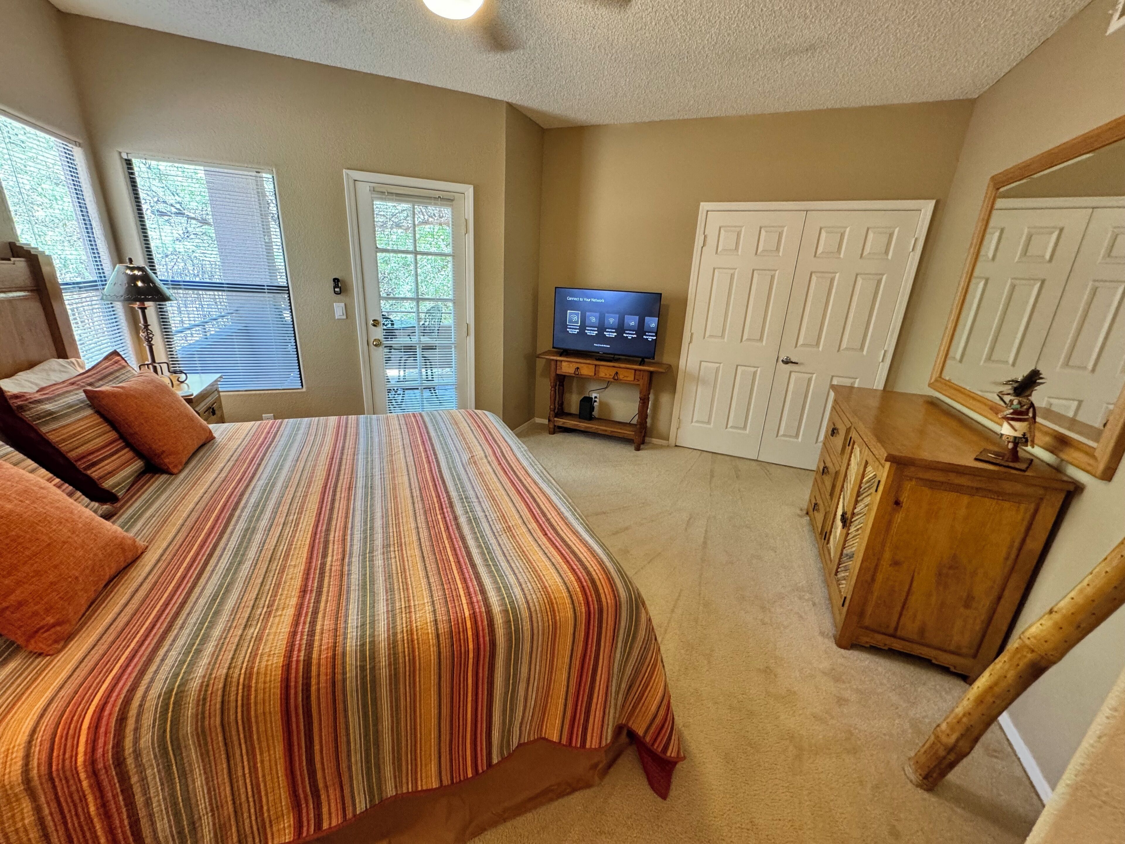 Ein Schlafzimmer mit Bett, Fernseher, Kommode und einer Tür.
