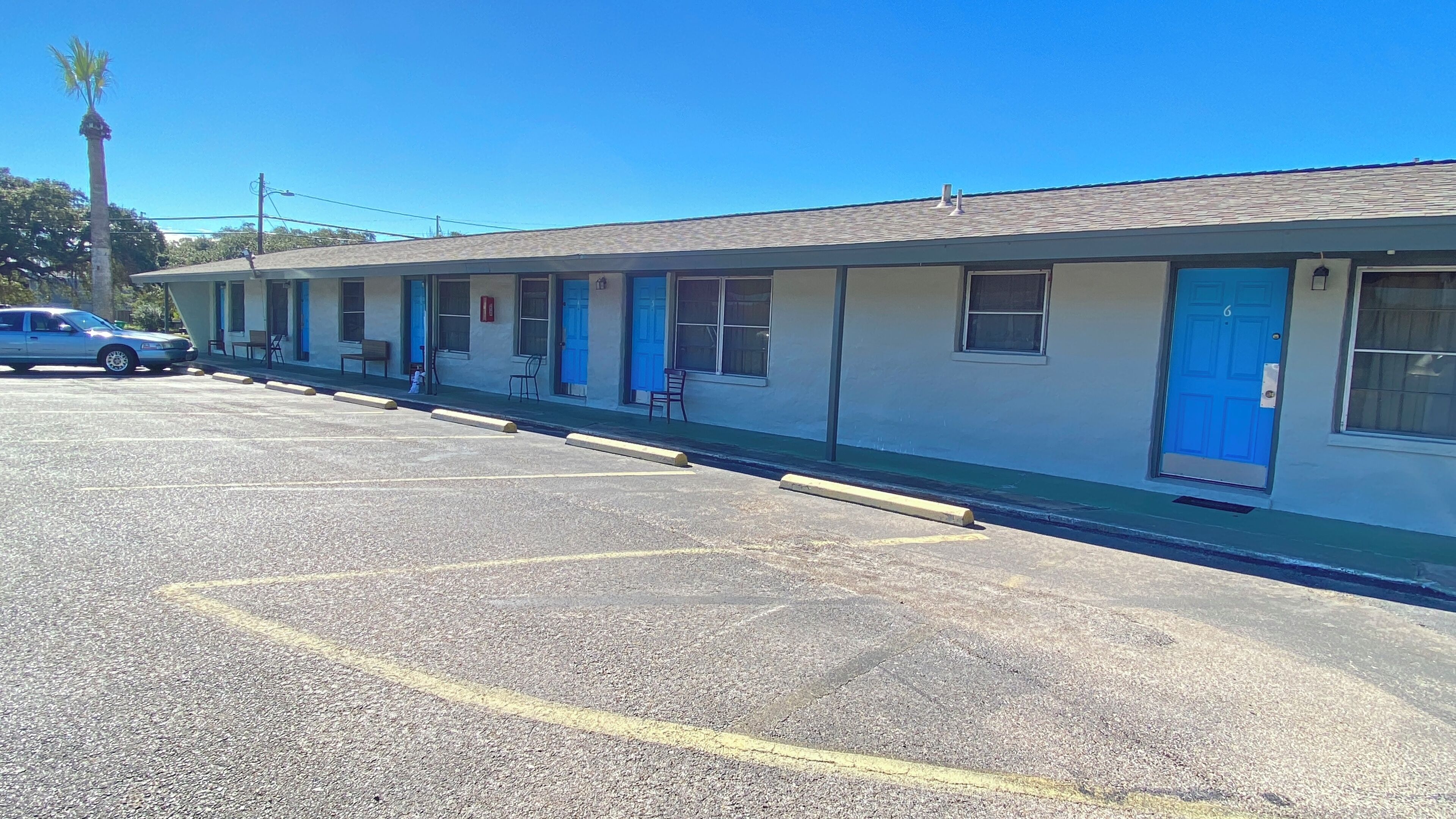 A motel with a row of rooms, each with a blue door and a small window.