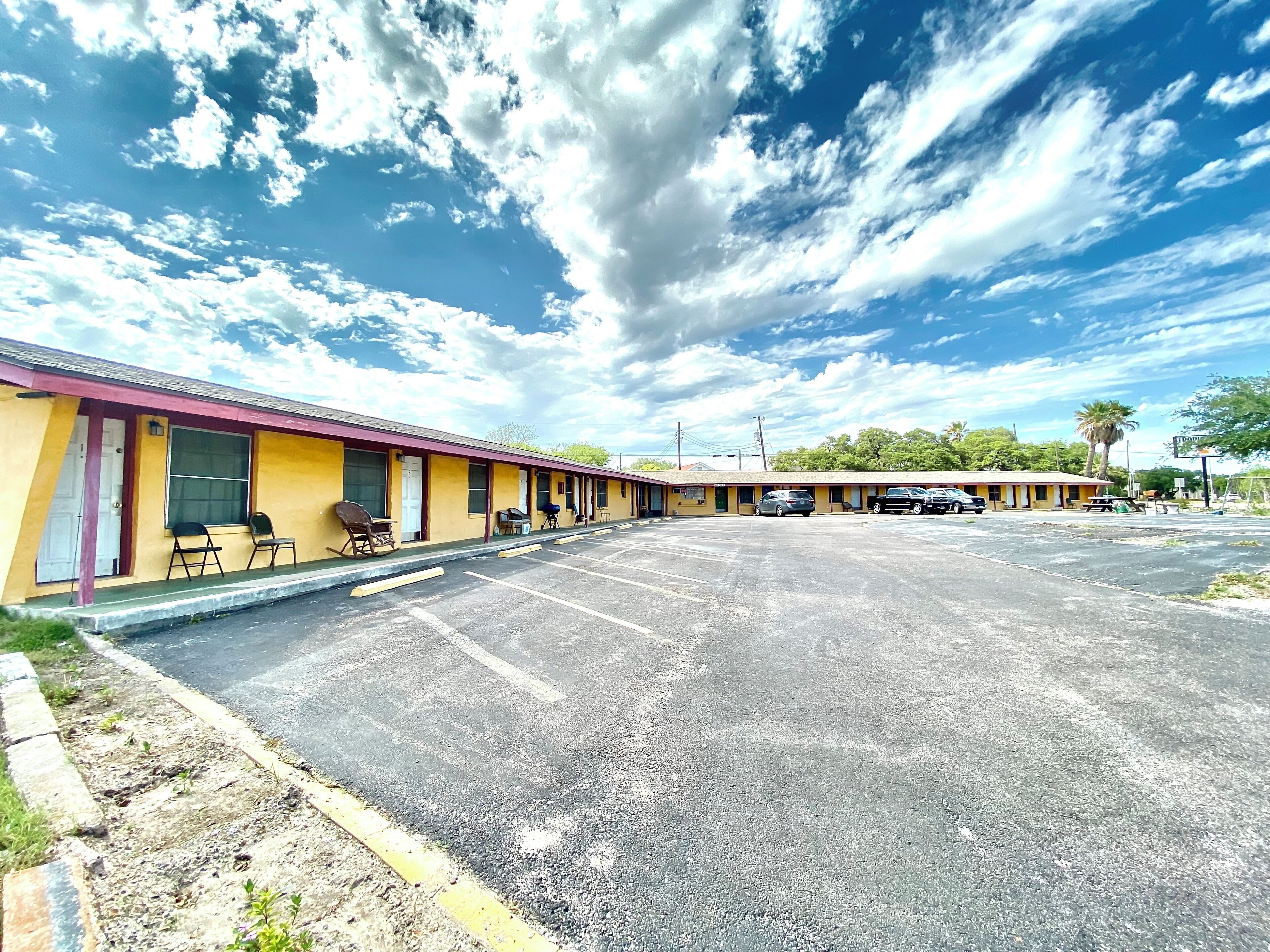 Un motel avec une rangée de chambres, un parking et un ciel dégagé.