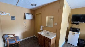 A small bathroom with a sink, mirror, and a microwave. - Tropic Motel (Aransas Pass)