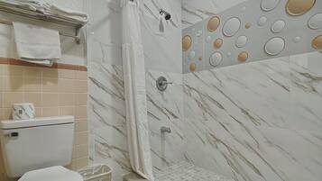 A bathroom with a toilet, shower, and tiled floor.