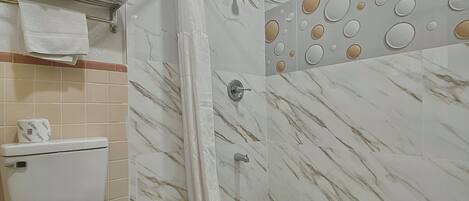 Une salle de bain avec des toilettes, une douche et un sol carrelé.