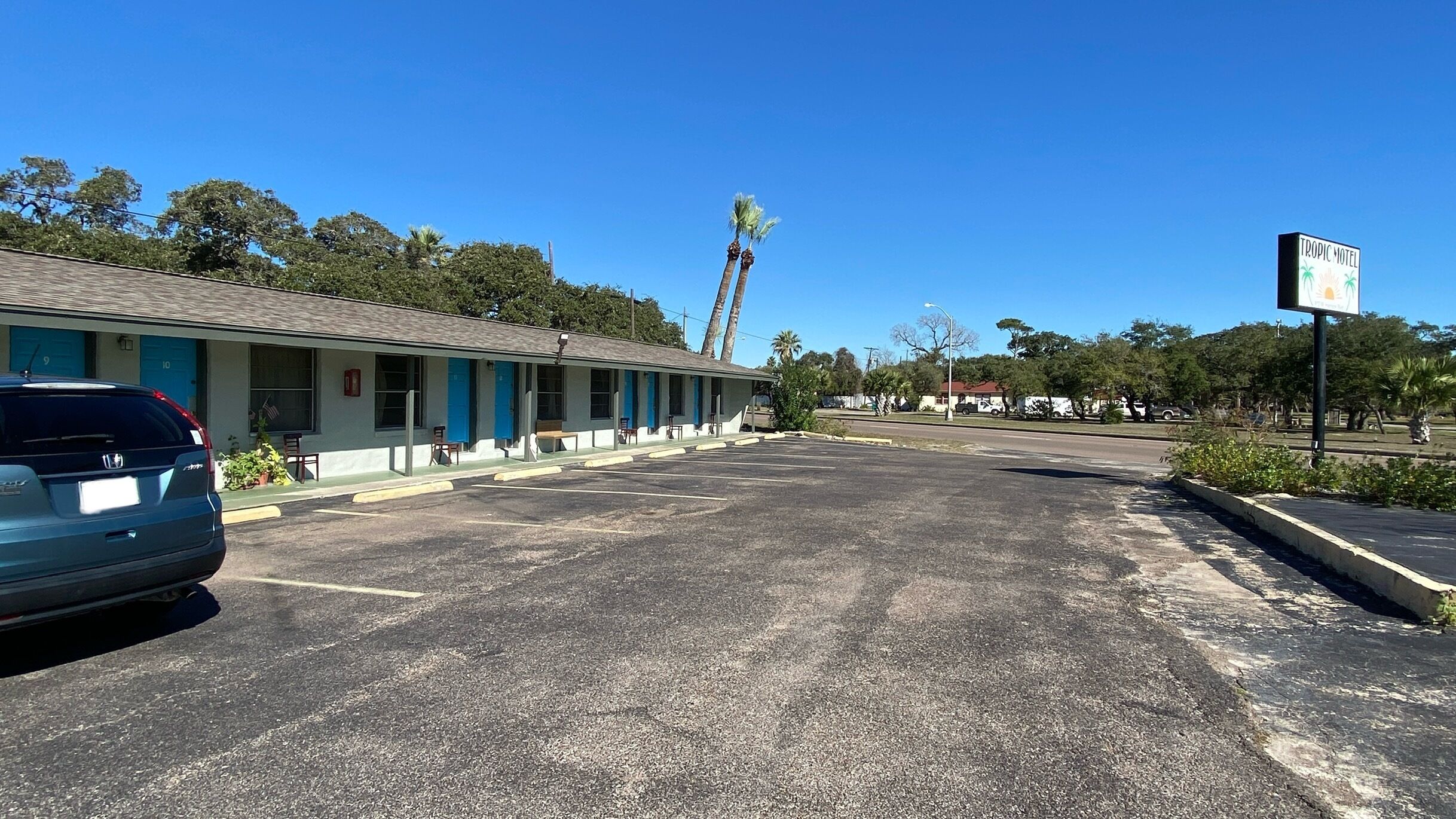A motel with a row of rooms, a parking lot, and a sign for the Tropic Hotel.