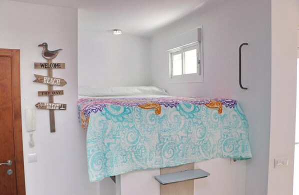 A bedroom with a bed, a window, a wooden sign with 'WELCOME' and 'BEACH' on it, and a wall-mounted telephone. - Apartment Malva in Conil (Conil de la Frontera)