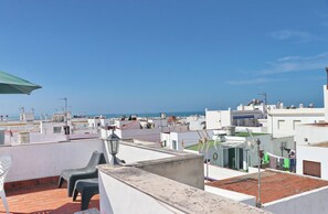 A rooftop terrace with a view of the sea, featuring a table and chairs, a lamp, and a clothesline with laundry. - Apartment Malva in Conil (Conil de la Frontera)