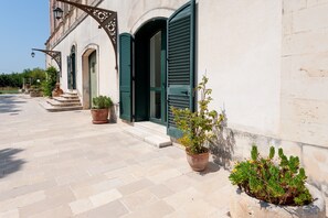 Un edificio con facciata in pietra, persiane verdi e piante in vaso.