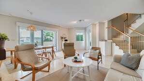 Un amplio salón con sofá, sillas, una mesa de centro y una escalera.