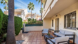 Un patio con mobiliario exterior, una palmera y vistas a edificios cercanos.