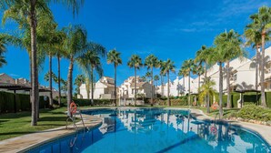 Una piscina rodeada de palmeras y edificios blancos.