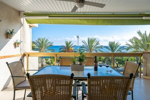 A covered outdoor dining area with a table, chairs, and potted plants.
