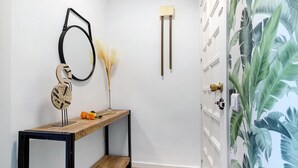 A hallway with a wooden bench, a wall-mounted mirror, and a door with a white doorbell. - Apartment 'Armonia' with Sea View, Wi-Fi and Air Conditioning (Torremolinos)
