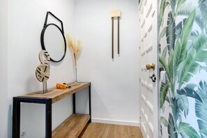 Un pasillo con un banco de madera, un espejo en la pared y una puerta con timbre blanco.
