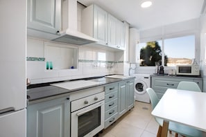 Una cocina moderna con horno integrado, lavadora y comedor con mesa y sillas.