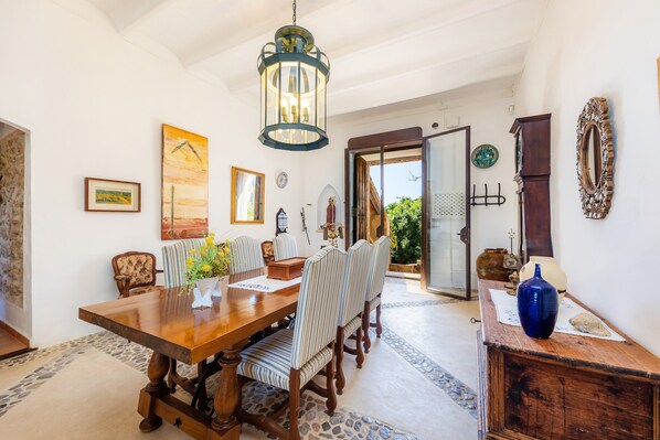 A dining area with a wooden table, striped chairs, and a hanging lantern.