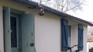 Une maison avec une porte verte, un vélo et un jardin où poussent des jonquilles.