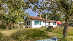 Une maison avec un toit rouge, des murs blancs et un petit patio aménagé avec du mobilier d’extérieur.