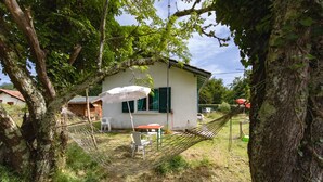 Une maison avec un hamac, une table et une chaise dans la cour.