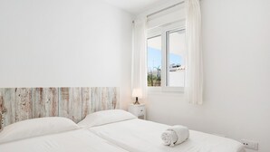 Ein Schlafzimmer mit einem Bett, einem Nachttisch, einer Lampe und einem Fenster mit Vorhängen.
