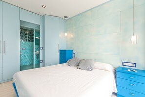 Un dormitorio con una cama, un aparador azul y un baño con pared de azulejos azules.