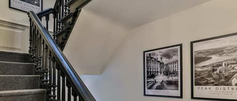 A staircase with a handrail and a wall with two framed black and white photographs.