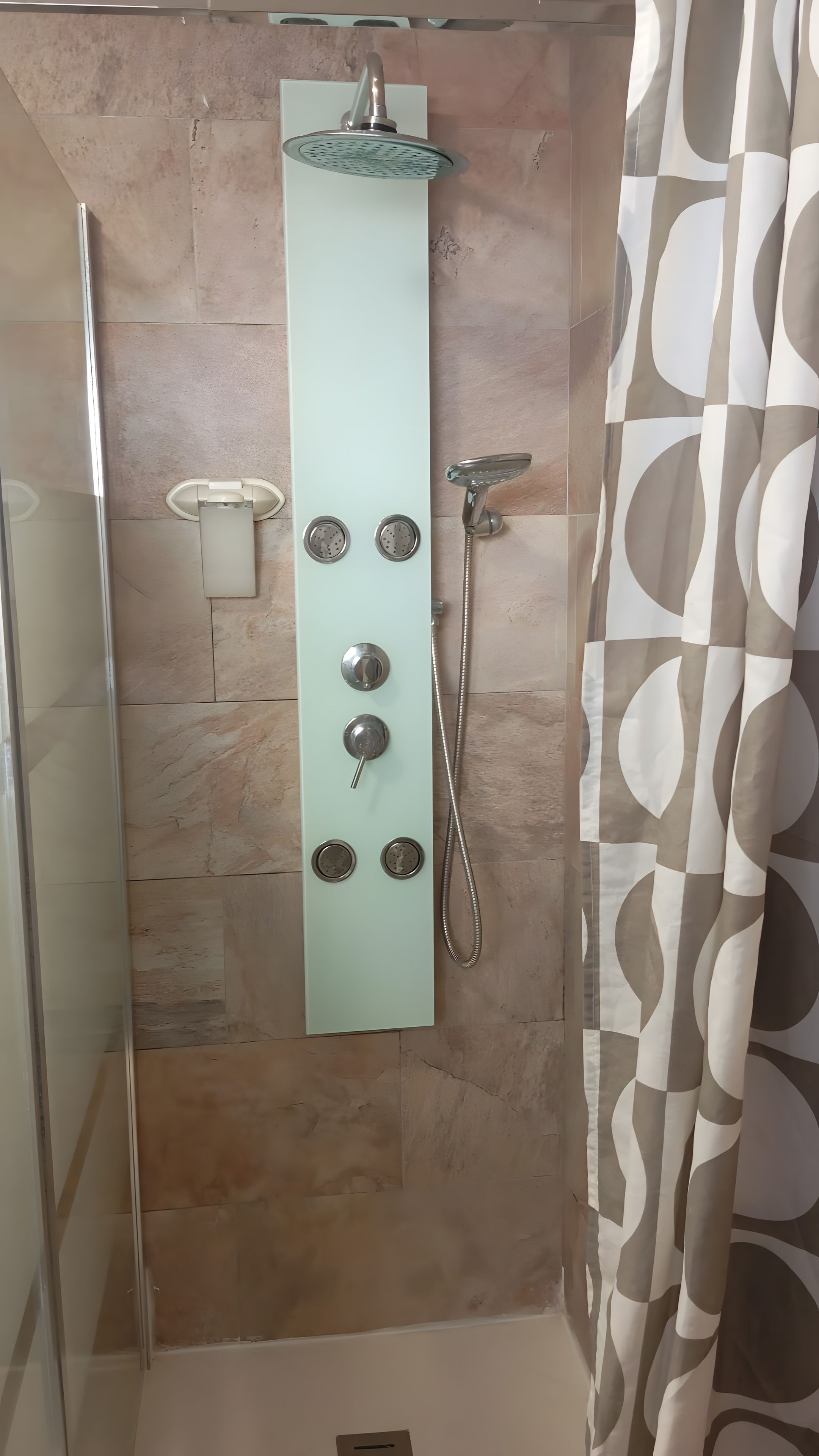 A shower with a glass enclosure, a handheld showerhead, and a wall-mounted control panel.