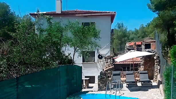 A swimming pool with a stone pathway leading to a patio area with outdoor furniture.