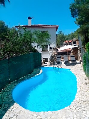 A swimming pool with a stone pathway leading to a patio area with outdoor furniture. - Holiday Home 'Casa Calafell' with Mountain View, Wi-Fi and Air Conditioning (SEGUR DE CALAFELL)
