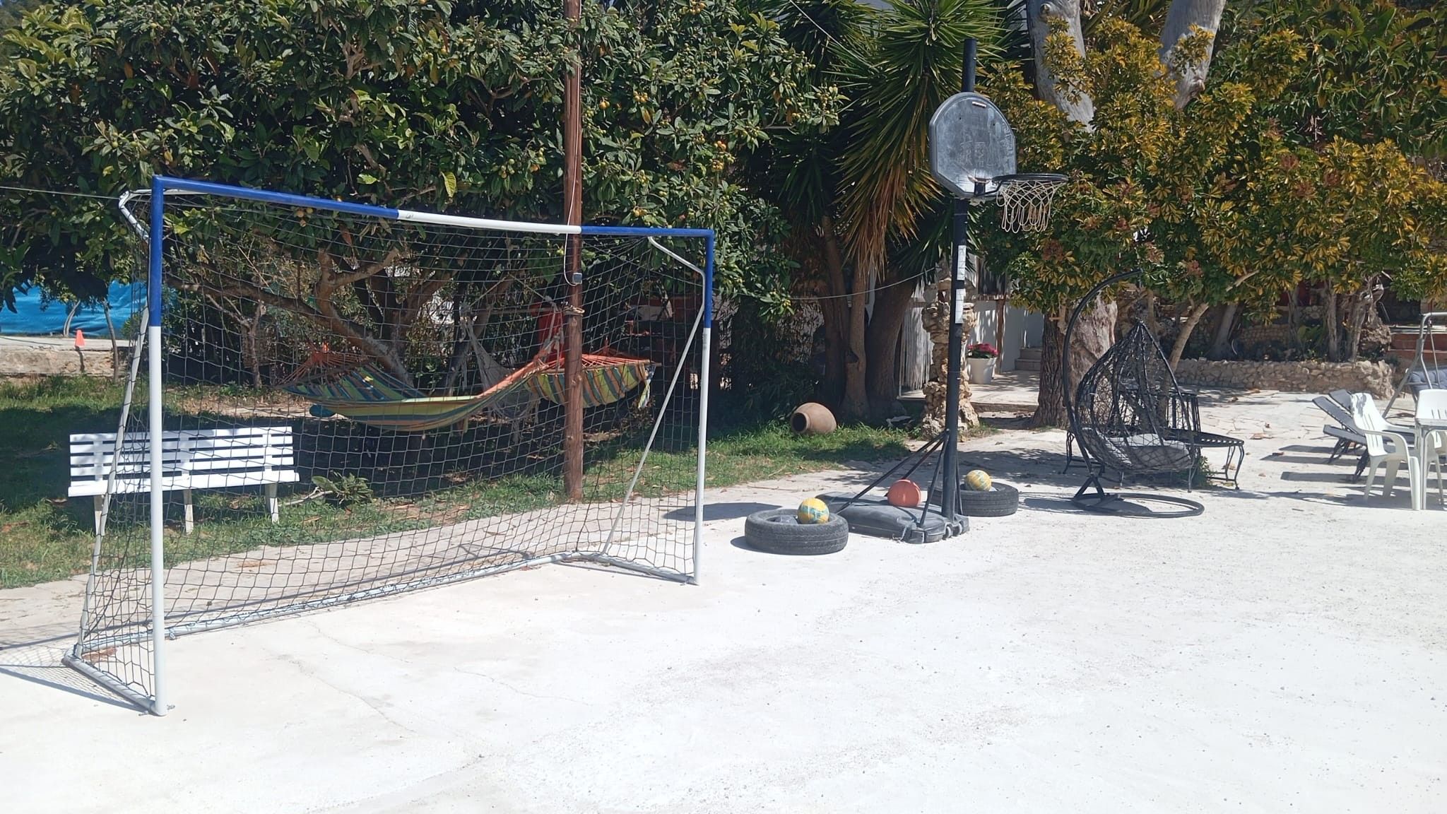 A sports court with a basketball hoop and a soccer goal.