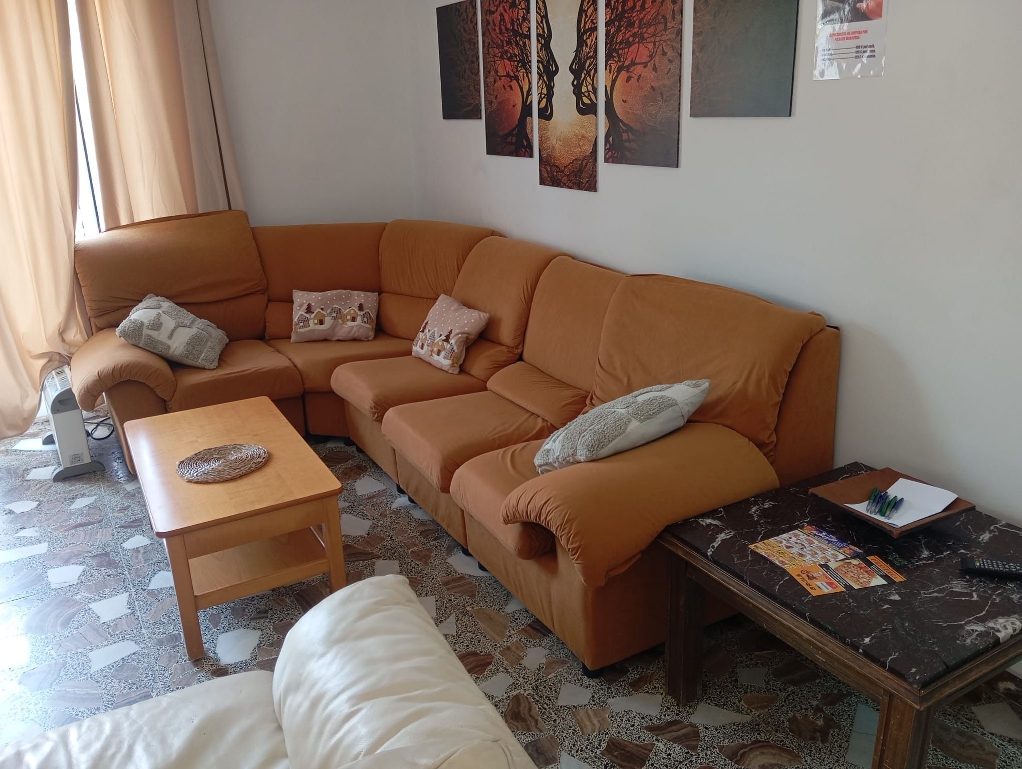 Uma sala de estar com um sofá marrom, uma mesa de centro de madeira, um sofá branco e uma mesa de mármore com revistas e canetas.
