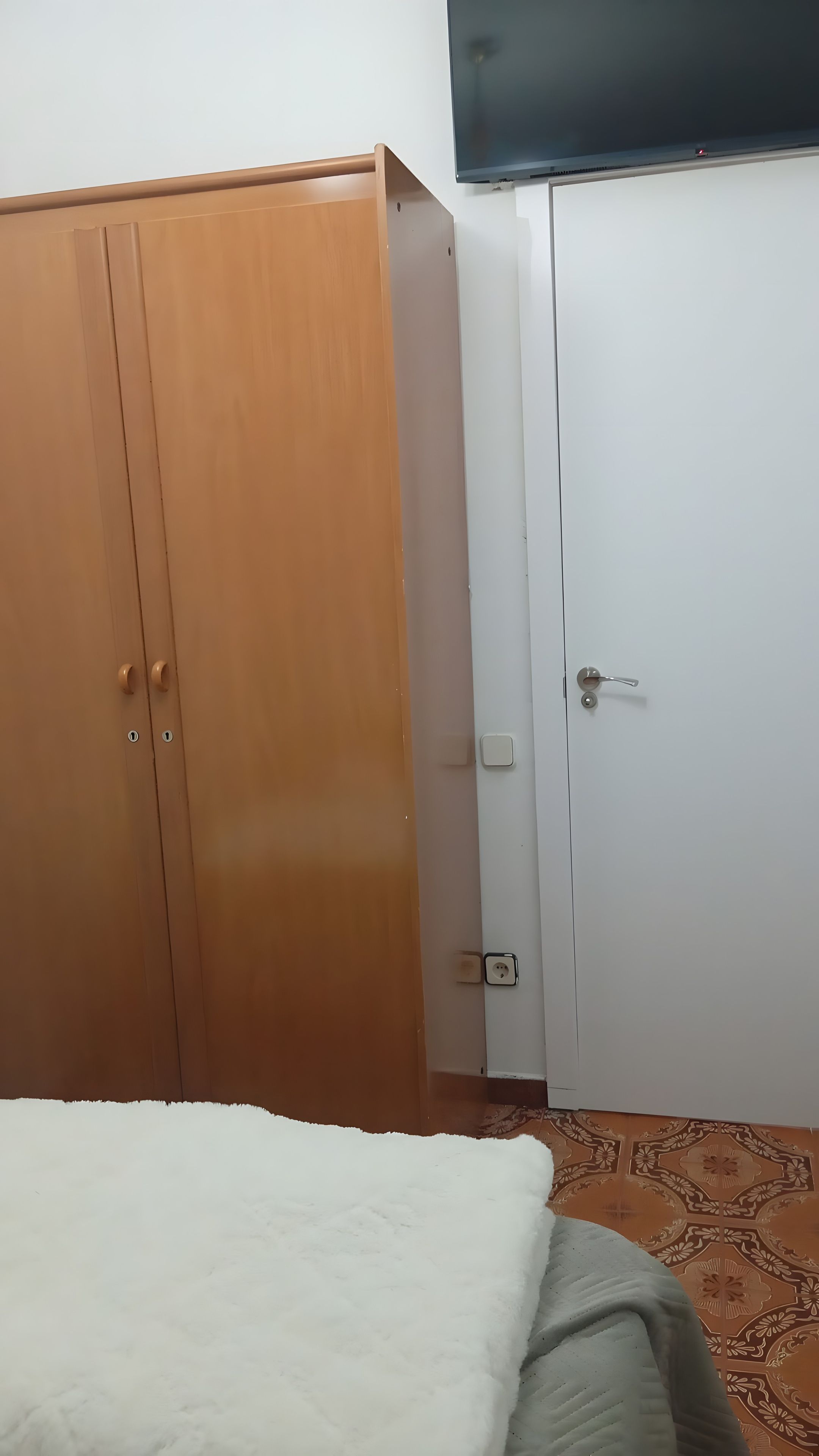 Una stanza con un armadio, un letto e una televisione.